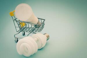 Fluorescent and LED light bulb with mini shopping cart photo