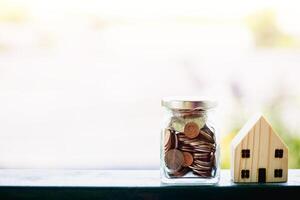 Wooden house model with money coins for business and property finance concept photo