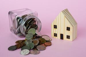 Wooden house model with money coins for business and property finance concept photo