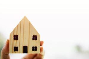 Hand holding wooden house model for housing concept photo