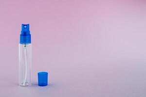 Transparent glass perfume and cosmetic spray bottle on pink background photo