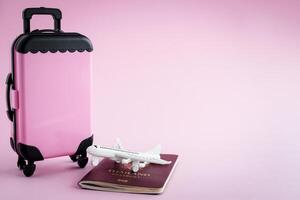 Pinky luggage with Thai passport and white airplane model on pink background photo