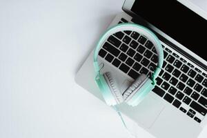 Top view of headphones with computer laptop on white office desk photo