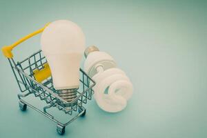 Fluorescent and LED light bulb with mini shopping cart photo