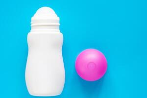 Female deodorant or roll on bottle with pink cover on blue background photo