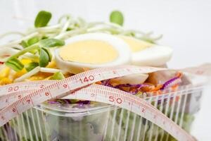 Close up of measuring tape with chicken egg and fresh salad vegetable photo