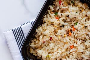 Delicious fried rice in lunch box with napery on marble background photo