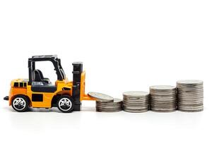 A yellow toy forklift with pile of coins on white background photo