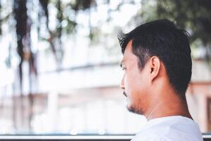 A lonely man sitting back and being absent-minded against blurred outdoor background photo