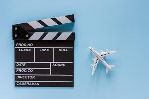 Movie clapper board and white airplane model on blue background photo