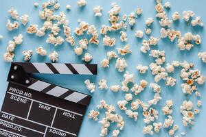 Movie clapper board with popcorn on blue background photo