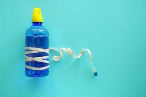 Bebiendo agua botella con medida cinta en azul antecedentes foto