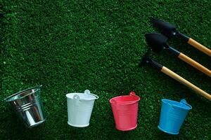 Gardening tools with tin pails or buckets on green grass background photo