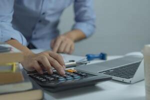 Businessman using calculator and accounting documents at desk with laptop computer. photo