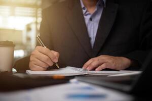 man hands with pen writing on notebook in the office.learning, education and work.writes goals, plans, make to do and wish list on desk. photo