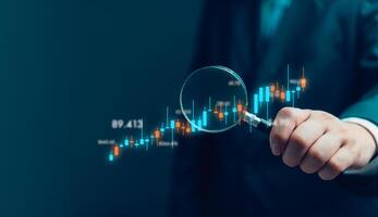 hand holding a magnifying glass with graph stock market. Business finance investment fun forex and exchange chart economic money photo