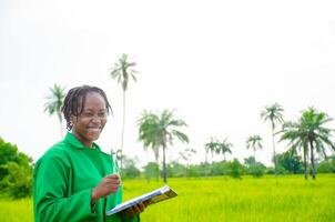 beautiful african student in the farm taking notes about her results in the farm photo