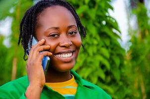 close up of a beautiful lady in the farm smiling as she is making call photo