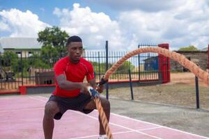 africano hombres con batalla cuerda batalla cuerdas ejercicio en el aptitud gimnasia. foto