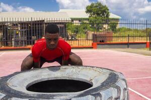 african Athletic man lifting a large gym tire in gym photo
