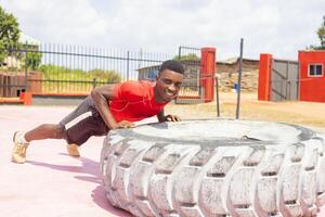 neumático dar la vuelta ejercicio. deportista es comprometido en rutina de ejercicio con pesado neumático en gimnasio foto