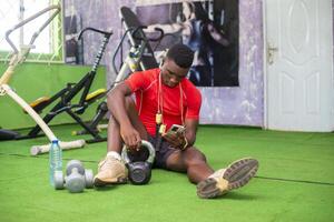 Black bodybuilder using mobile phone at gym to check things online photo