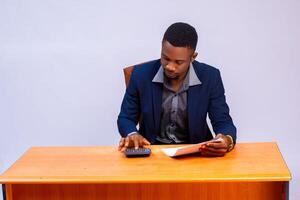 handsome african accountant in the office going the calculation on his invoice photo