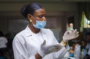 beautiful african doctor look at the vaccine at her hand photo