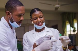 two african doctors pointing at vaccine against corona virus photo