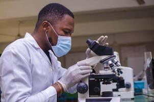 young scientist looking through a microscope in a laboratory. Young scientist doing some research. photo