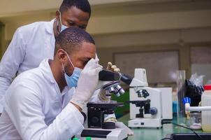 Scientists studying a virus ,looking through microscope photo