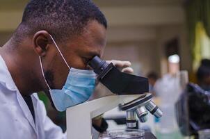 handsome lab technician or scientists working in laboratory looking through microscopes photo