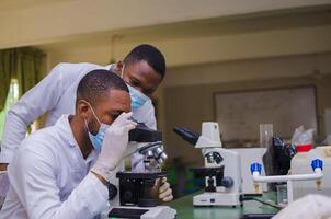 two Scientists studying a virus ,looking through microscope photo