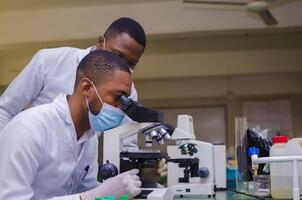 equipo científico de investigación bioquímica que trabaja con microscopio para el desarrollo de vacunas contra el coronavirus en laboratorios de investigación farmacéutica, enfoque selectivo foto