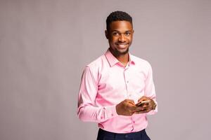 hermoso africano hombre en aislado terminado blanco antecedentes sonriente como él opera su teléfono foto