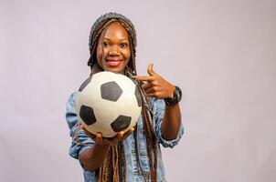 hermosa africano dama sonriente como ella puntos a el pelota en su mano foto