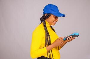 pretty african lady smiling while holding and showing a point of sale photo