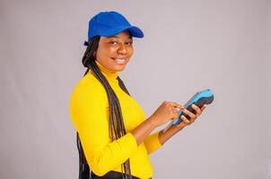 pretty black lady smiling while holding and showing a point of sale device photo