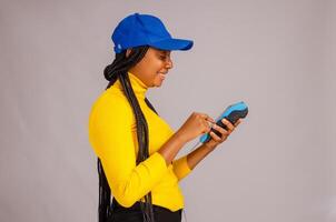 pretty black lady smiling while holding and showing a point of sale device photo