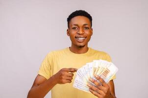 young african guy smiling as he points to the money on his hand photo