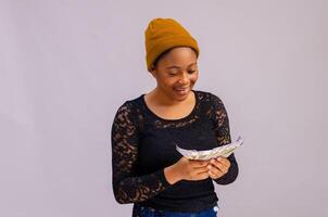 excited and happy african lady holding and pointing to a lot of money photo