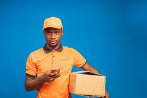 delivery man using his cellphone while holding a delivery package on his hand photo