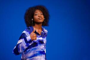 Gorgeous lady listening music in headphones and singing on blue background. photo