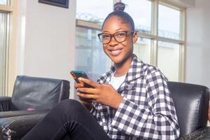 Portrait of the beautiful Young woman Using Smartphone, Browsing in Internet, Checking Social Networks, Scrolling Newsfeed while Sitting At Home. photo