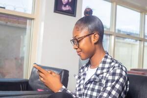 Happy young businesswoman using mobile phone while relaxing on a couch at home photo