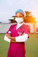 image of black nurse with face mask-young African health worker with stethoscope around the neck-portrait of beautiful African student nurse in her scrub dress photo