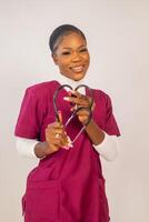 close up of a beautiful nurse smiling as she did love shape with her stethoscope photo