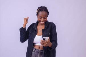 young black woman using her phone looking surprised photo