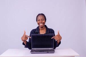retrato de un emocionado hermosa joven negro mujer señalando a su ordenador portátil pantalla foto