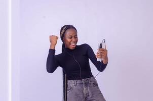 Young woman using phone for listening to music on white background photo